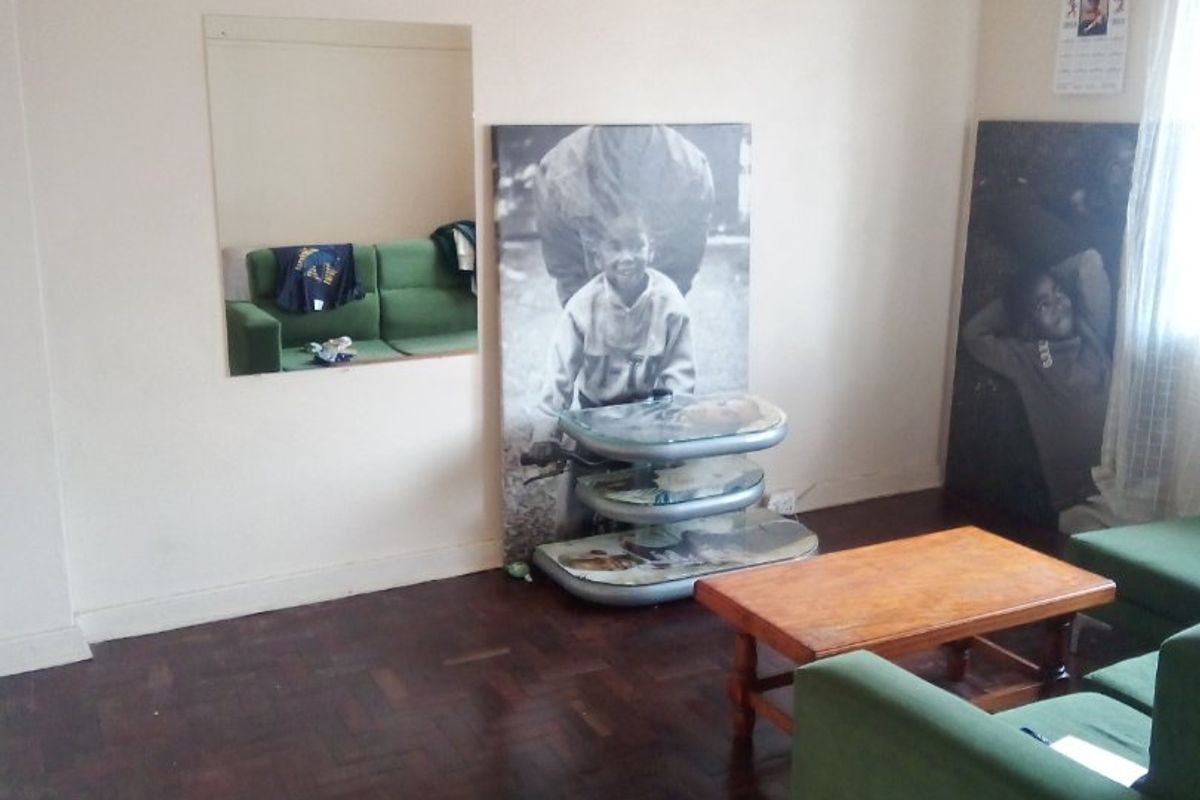 A living room featuring original parquet flooring, a built-in wall mirror, and high ceilings with traditional picture rails.
