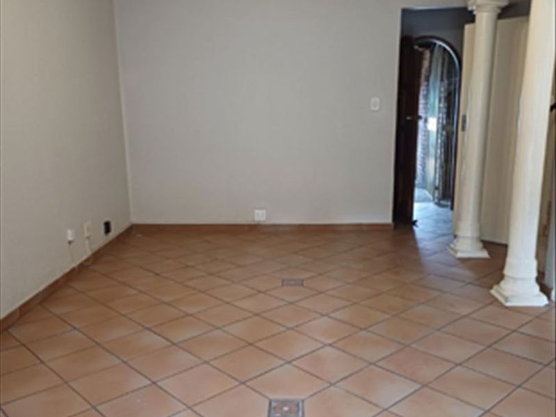 An empty living room featuring ceramic tile flooring, decorative columns, and a ceiling fan, offering a blank canvas for interior design.