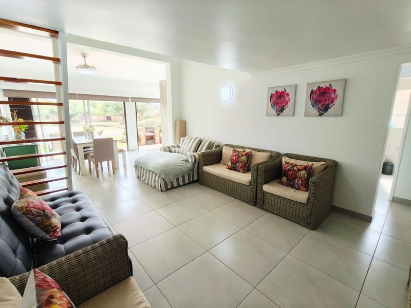 Spacious open-plan living and dining area featuring tiled flooring, a modern staircase, and large sliding doors leading to an outdoor patio space.