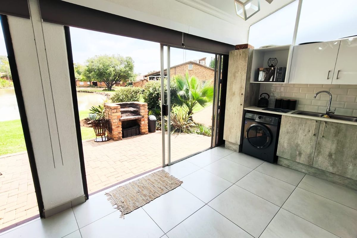 Modern kitchen featuring built-in cabinetry, subway tile backsplash, and seamless flow to an outdoor patio area with a built-in brick braai.