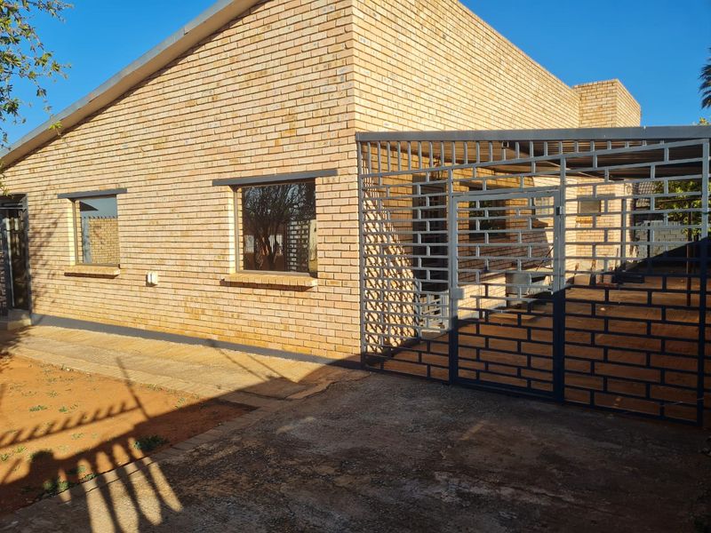 Front exterior view of a face brick house featuring a metal security gate and paved driveway area.