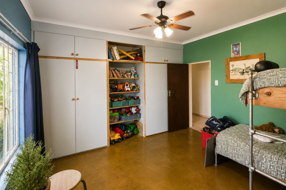 A bedroom featuring polished concrete floors, a ceiling fan, and extensive built-in cabinetry with integrated open shelving.