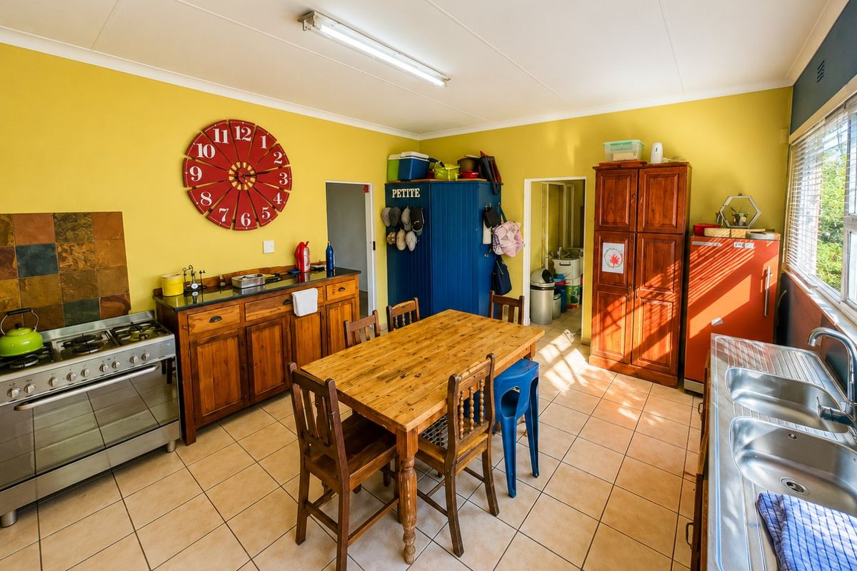 A functional kitchen featuring tiled flooring, a gas stove with extractor, and a double bowl stainless steel sink with wooden cabinetry.