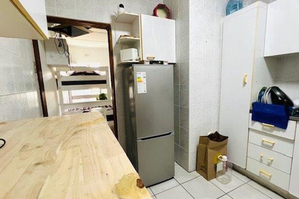 Compact kitchen featuring tiled walls, built-in cabinetry, and a wooden countertop, providing a functional workspace within the apartment.