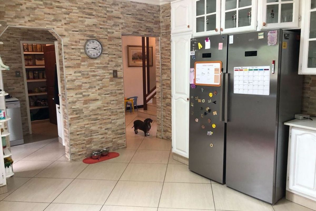 Kitchen area featuring stone veneer wall accents, tiled flooring, and built-in cabinetry, with an adjacent pantry or utility space visible through an archway.