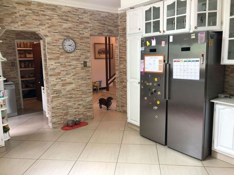 Kitchen area featuring stone veneer wall accents, tiled flooring, and built-in cabinetry, with an adjacent pantry or utility space visible through an archway.