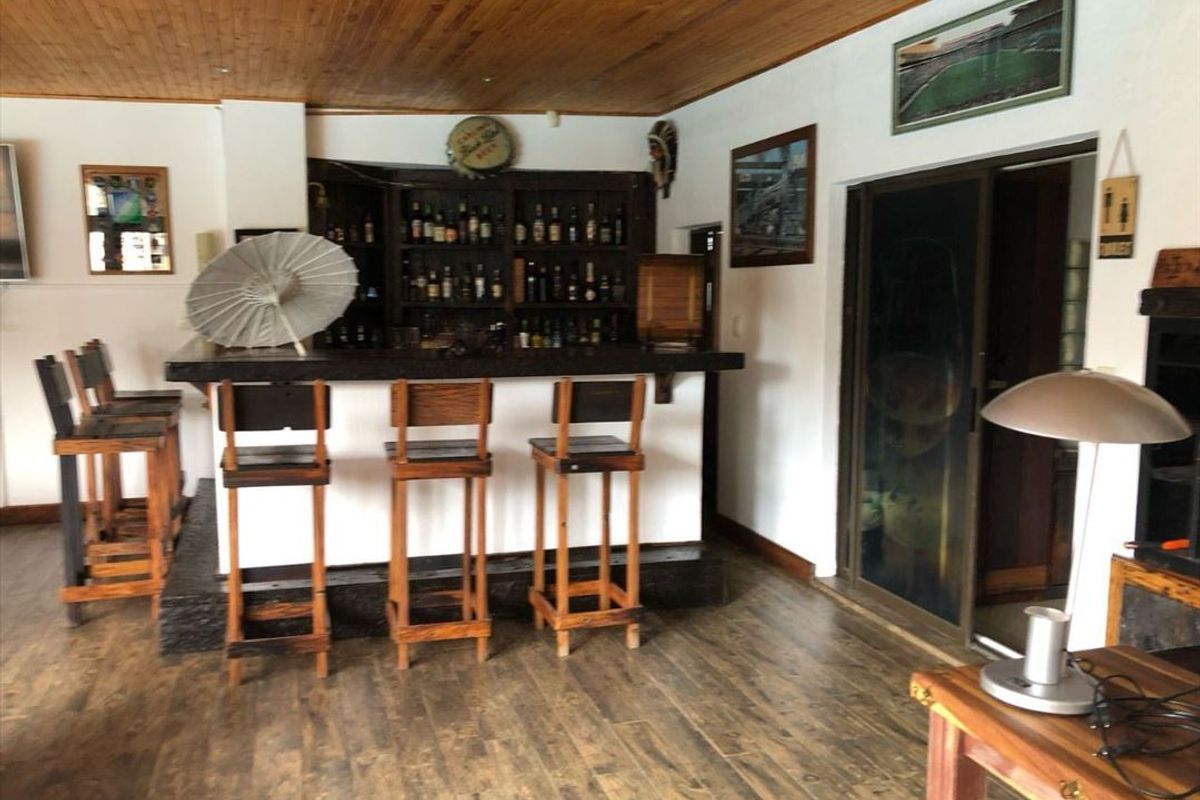 A dedicated home bar area featuring a built-in bar counter, timber-clad ceiling, and sliding glass door access.