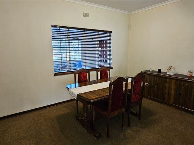A functional dining room featuring carpet flooring, coving, and venetian blinds, providing a neutral space ready for modern updates.
