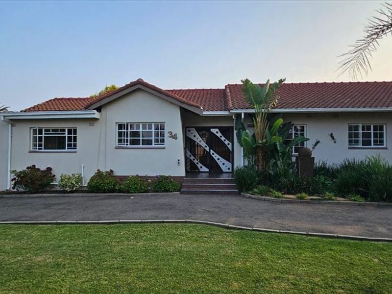 A well-maintained single-story residential property featuring a tiled roof, paved driveway, and established front garden with secure gated entrance.