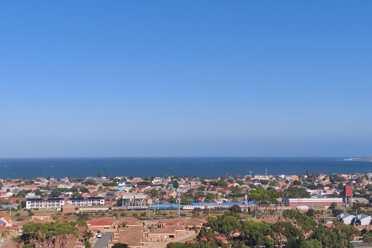 A wide-angle elevated view overlooking a coastal residential neighborhood with the ocean visible in the background.