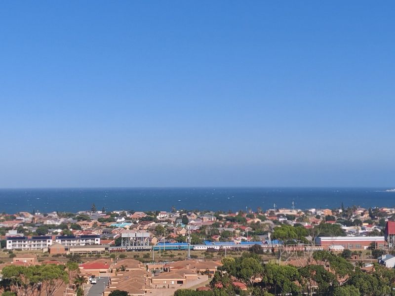 A wide-angle elevated view overlooking a coastal residential neighborhood with the ocean visible in the background.