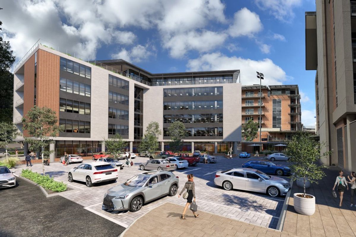 A modern multi-story commercial office building featuring a glass and brick facade with an integrated paved parking area.