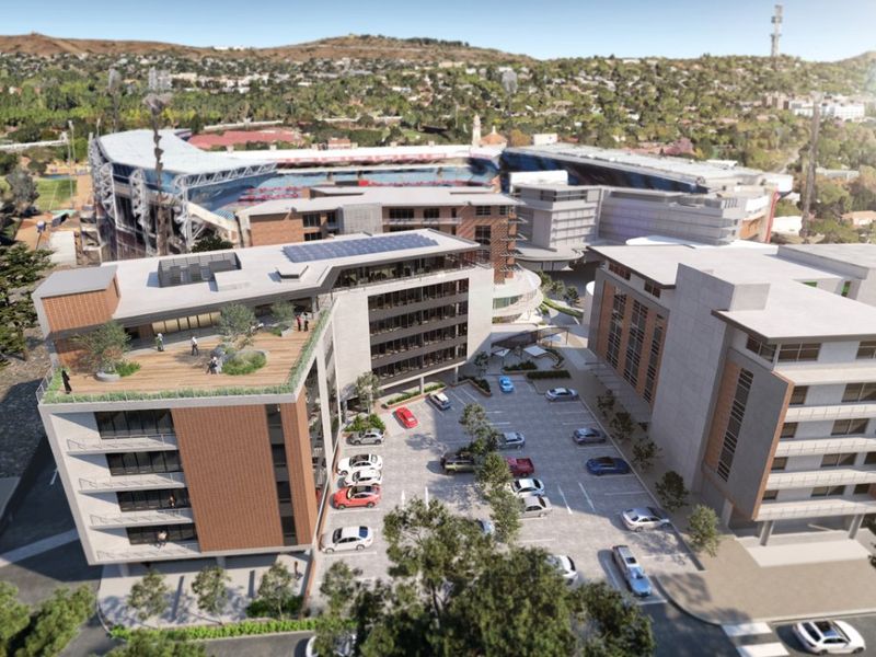 Aerial view of a modern commercial office complex featuring multi-story buildings, rooftop terraces, and an integrated parking area.