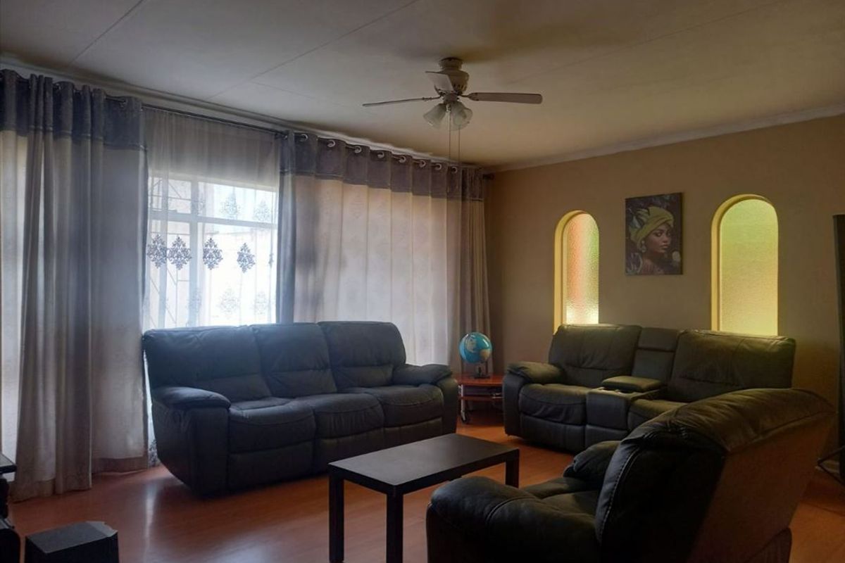 A comfortable living room featuring laminate flooring, a ceiling fan, and distinctive arched wall niches, providing a warm and inviting atmosphere.
