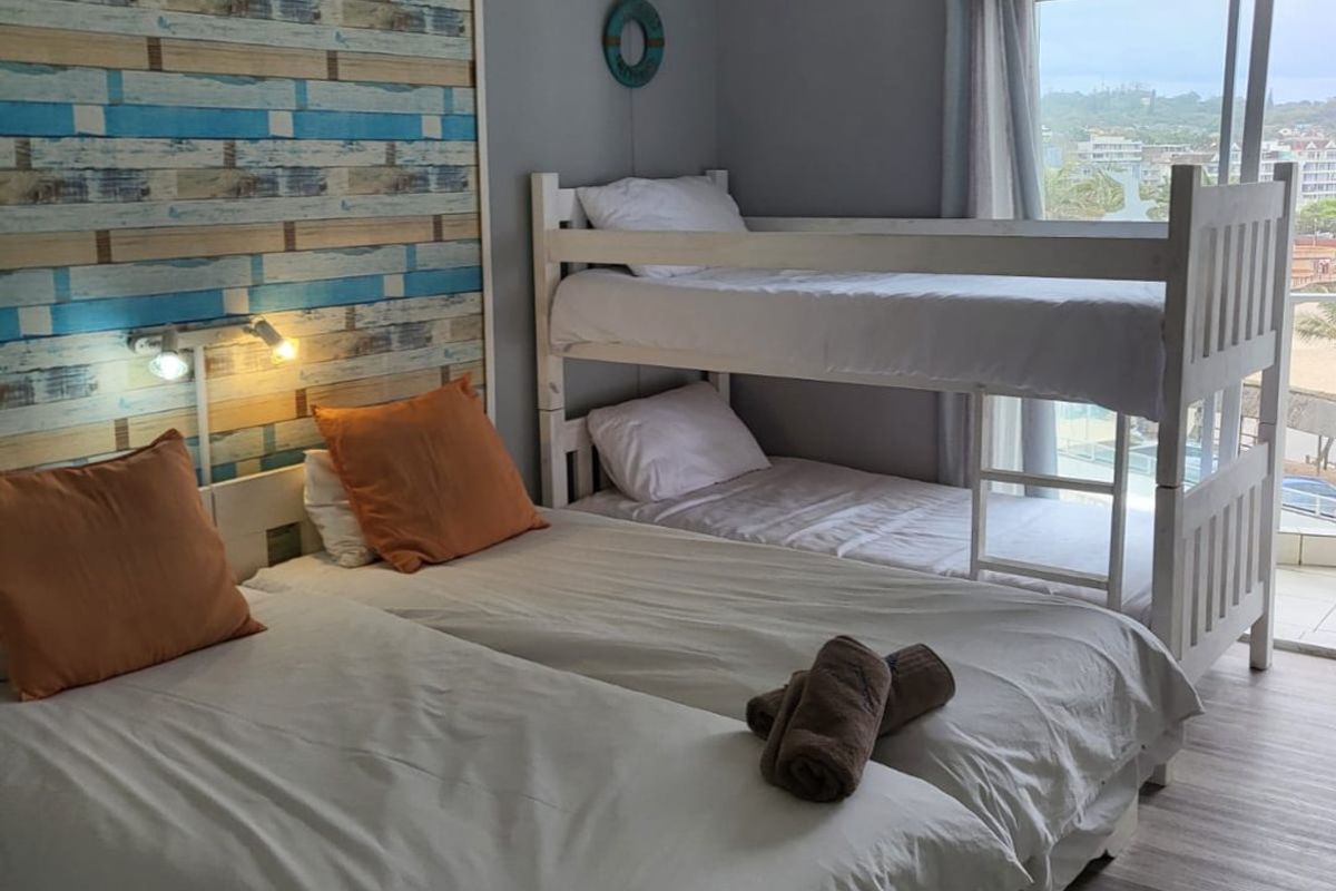 A bedroom featuring laminate flooring, a ceiling fan, and a sliding glass door providing access to a balcony with an exterior view.