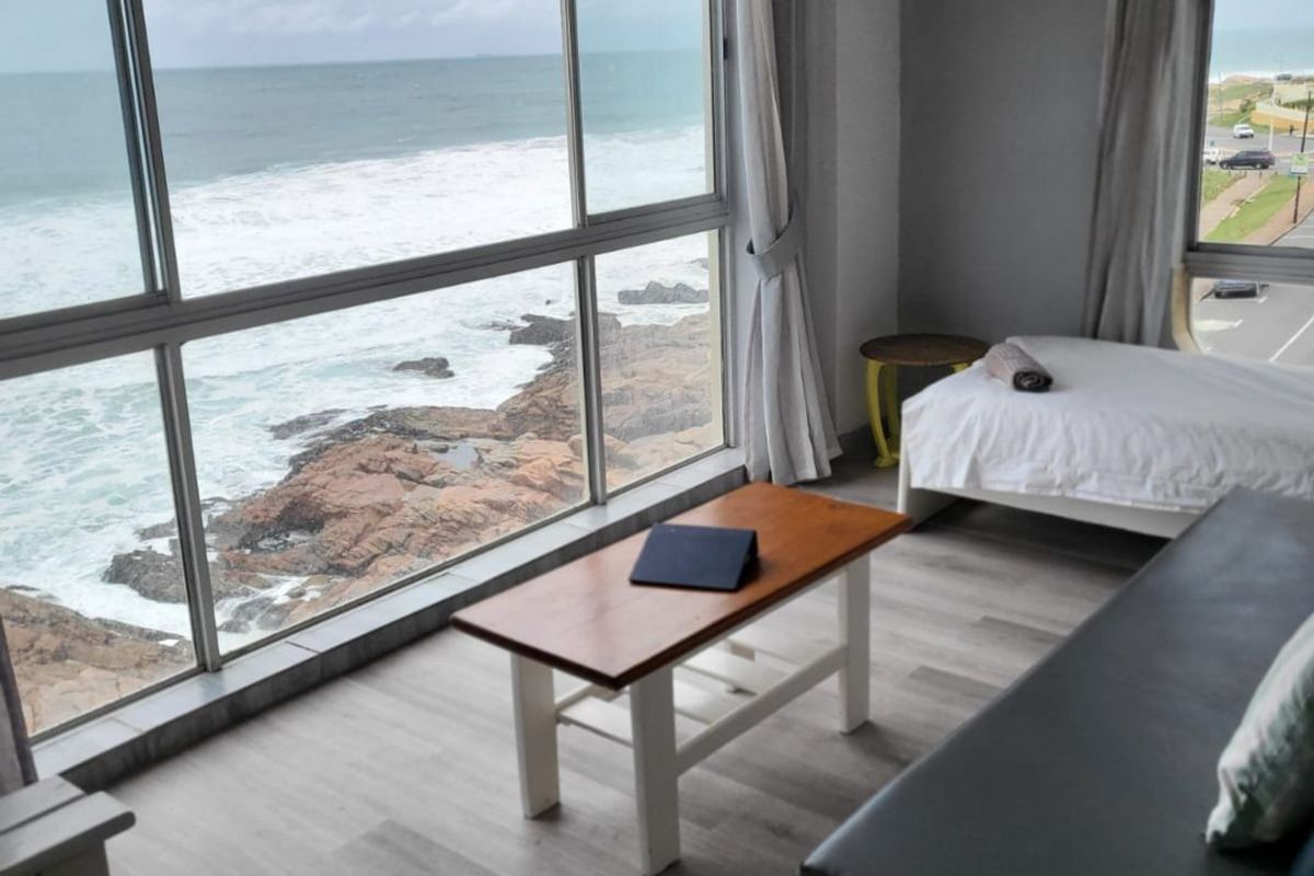 Living area featuring expansive floor-to-ceiling windows with direct ocean views and modern laminate flooring.