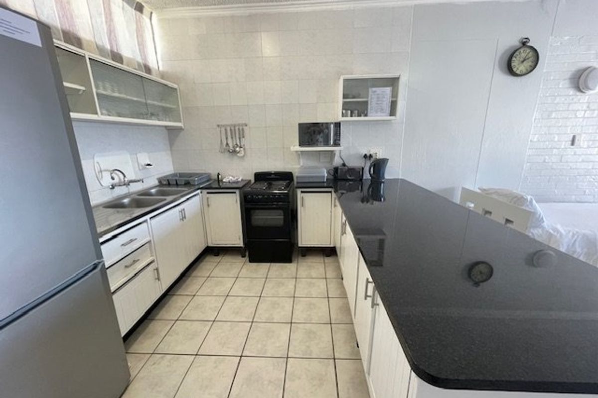 A functional kitchen featuring granite countertops, a double bowl sink, tiled backsplash, and a freestanding stove with ample built-in cabinetry.