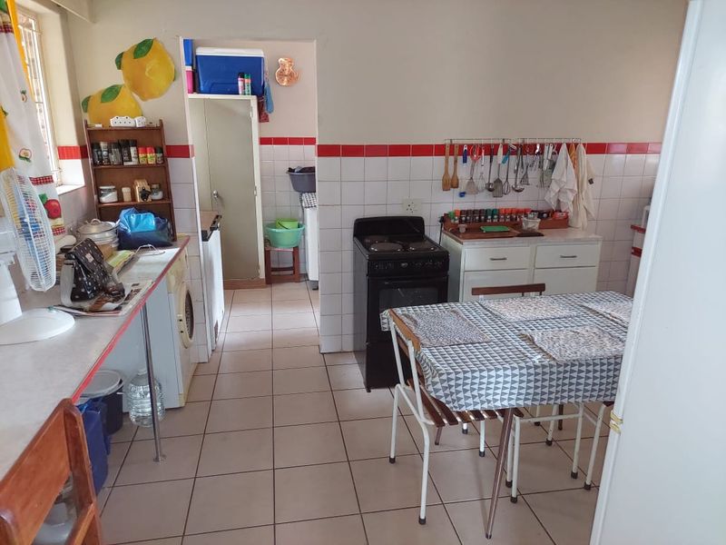 A functional kitchen area featuring tiled flooring, a freestanding stove, and a small adjacent scullery or utility space.