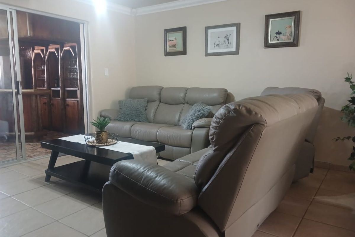 A comfortable living room featuring tiled flooring, cove cornicing, and a sliding door providing access to an adjacent built-in bar area.