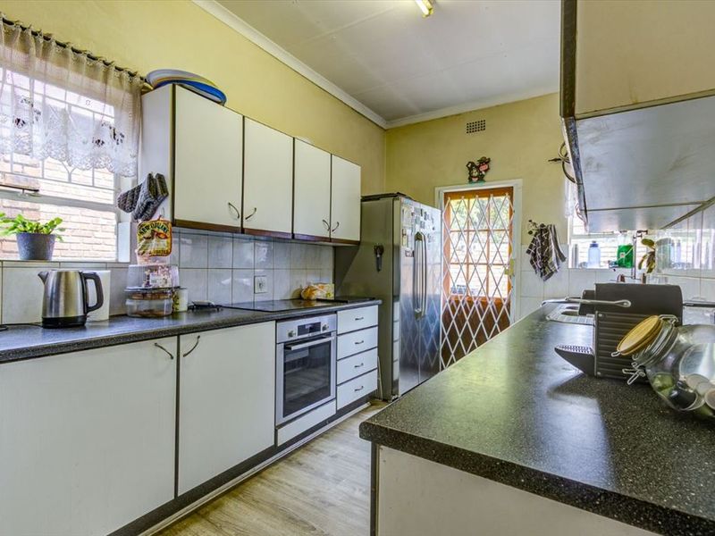 A functional kitchen featuring laminate countertops, built-in oven, electric hob, and tiled splashbacks, offering a practical layout with direct access to the exterior.