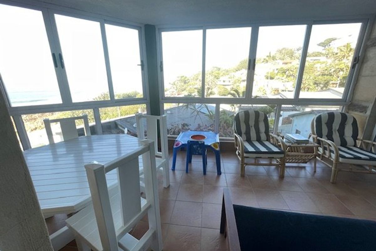 An enclosed balcony featuring tiled flooring and large aluminum sliding windows, offering expansive views and natural light.