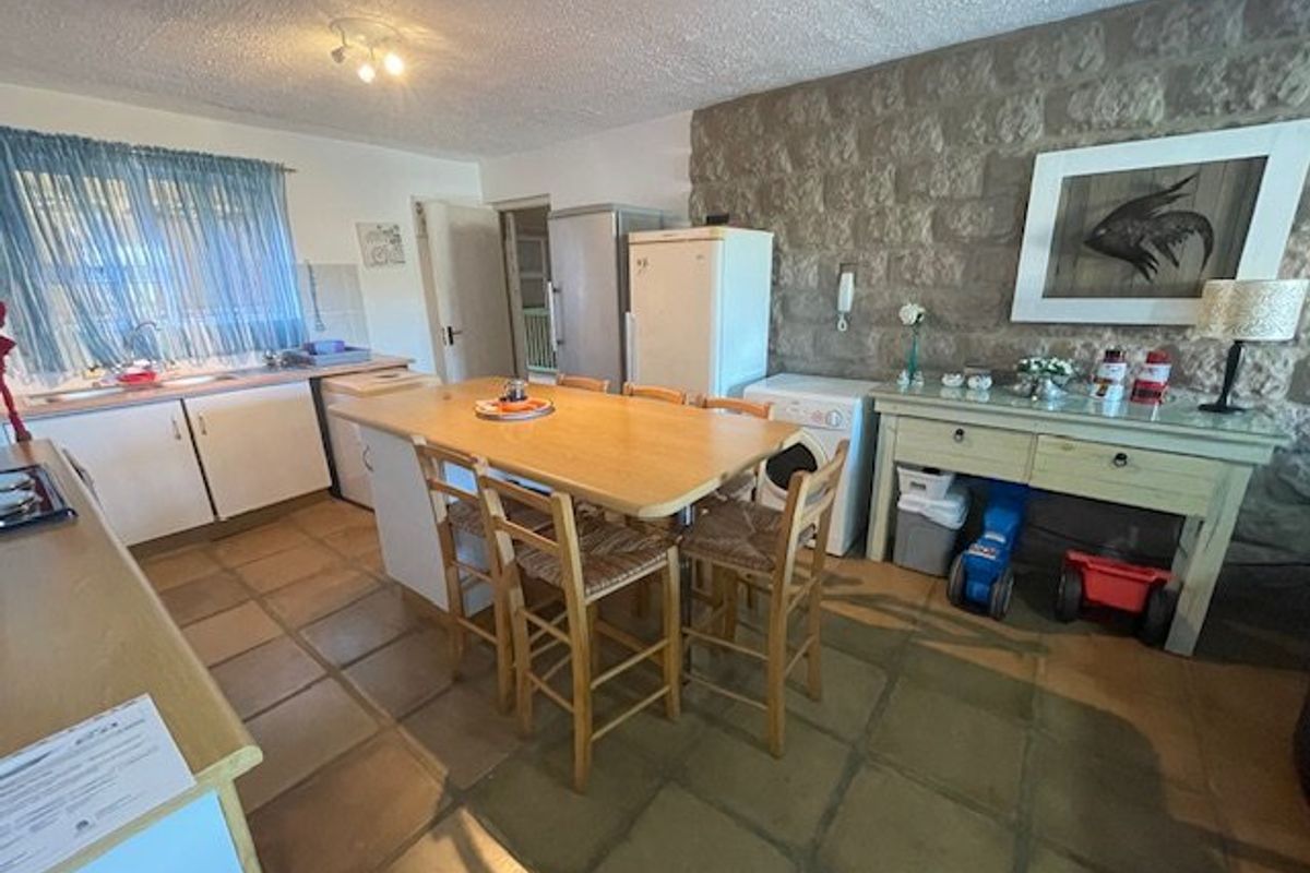 A dated kitchen featuring a prominent stone feature wall, tiled flooring, and a central island, offering potential for a modern renovation.