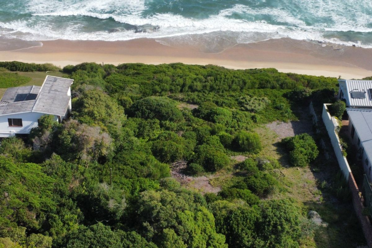 Aerial view of a vacant residential plot situated along the coastline, featuring dense natural vegetation and direct proximity to the beach.