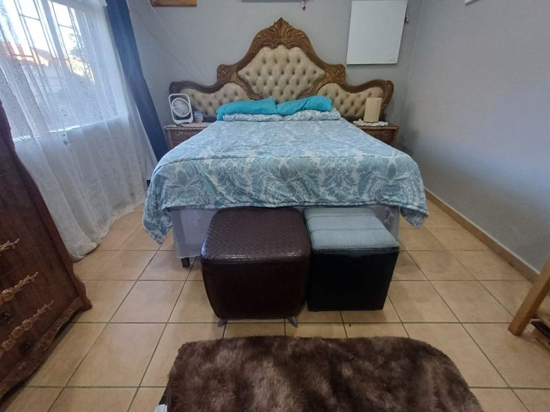 A bedroom featuring tiled flooring and a window with security bars, providing a functional space for rest.