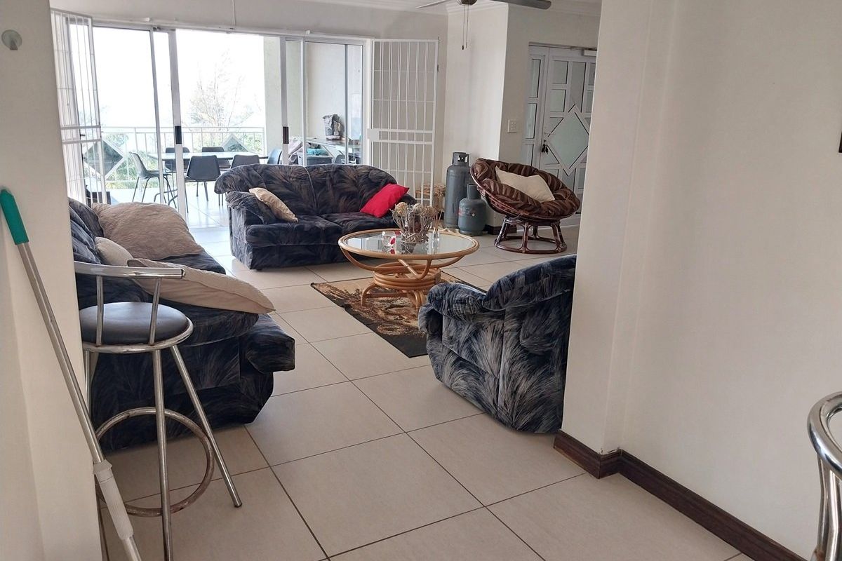 Spacious living area featuring neutral tiled flooring, a ceiling fan, and large sliding glass doors that provide access to an outdoor patio space.