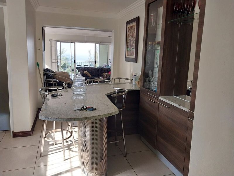 A dedicated bar area featuring built-in cabinetry, a granite countertop, and tiled flooring, providing a functional space for entertaining.