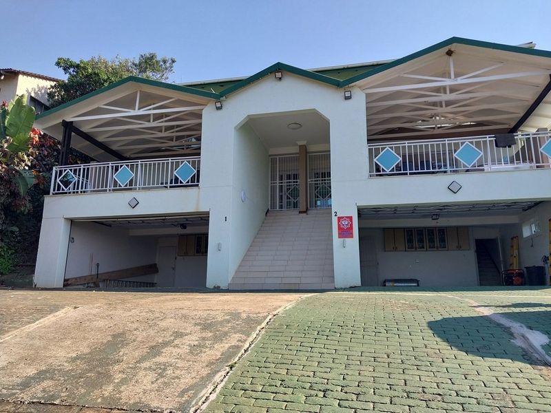 Front elevation of a multi-level house featuring a double garage, central staircase leading to an entrance, and covered balconies on the upper level.
