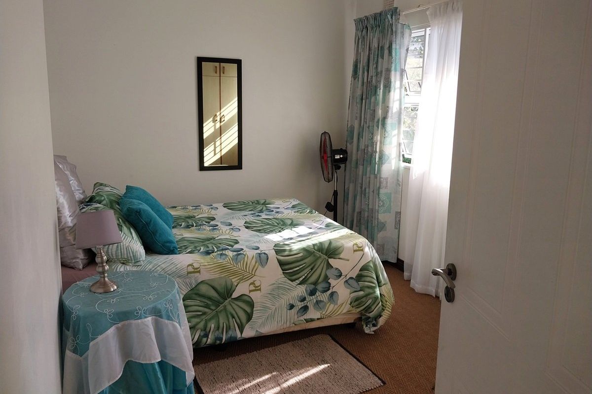 A standard bedroom featuring carpeted flooring and a louvered window with curtain tracks, providing natural light.