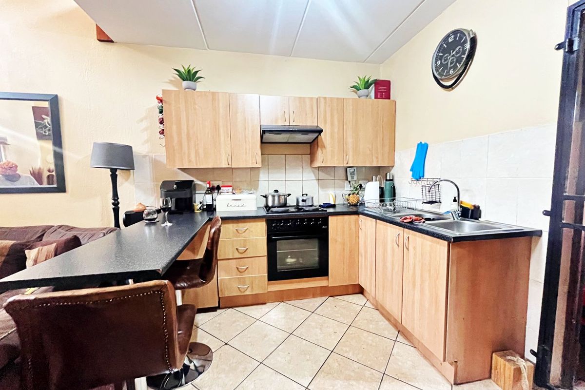 Functional kitchen featuring laminate cabinetry, built-in oven with extractor fan, tiled backsplash, and a breakfast bar extension.