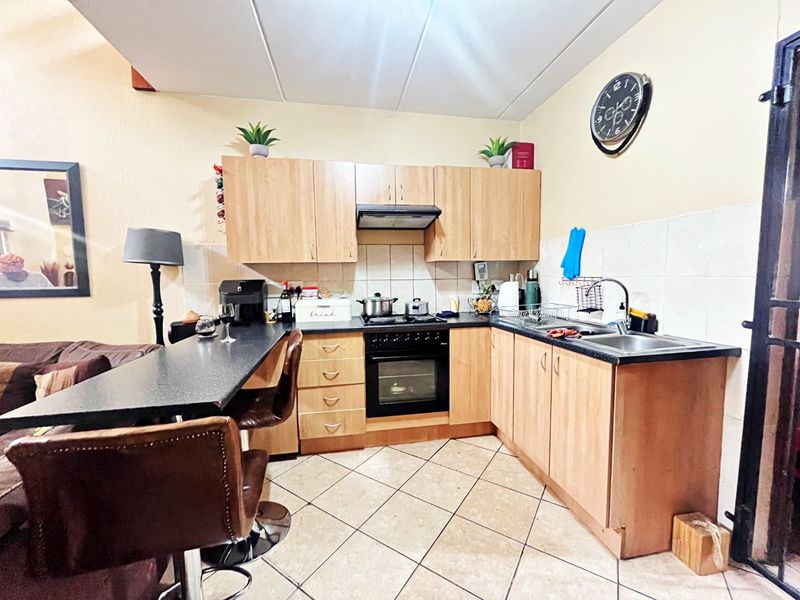 Functional kitchen featuring laminate cabinetry, built-in oven with extractor fan, tiled backsplash, and a breakfast bar extension.