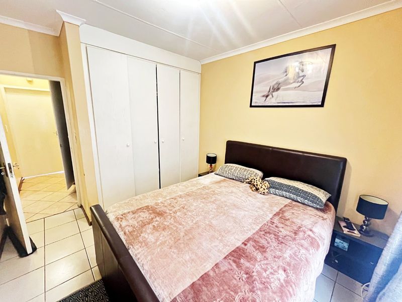 A functional bedroom featuring built-in cupboards, tiled flooring, and neutral wall finishes, providing a practical living space.
