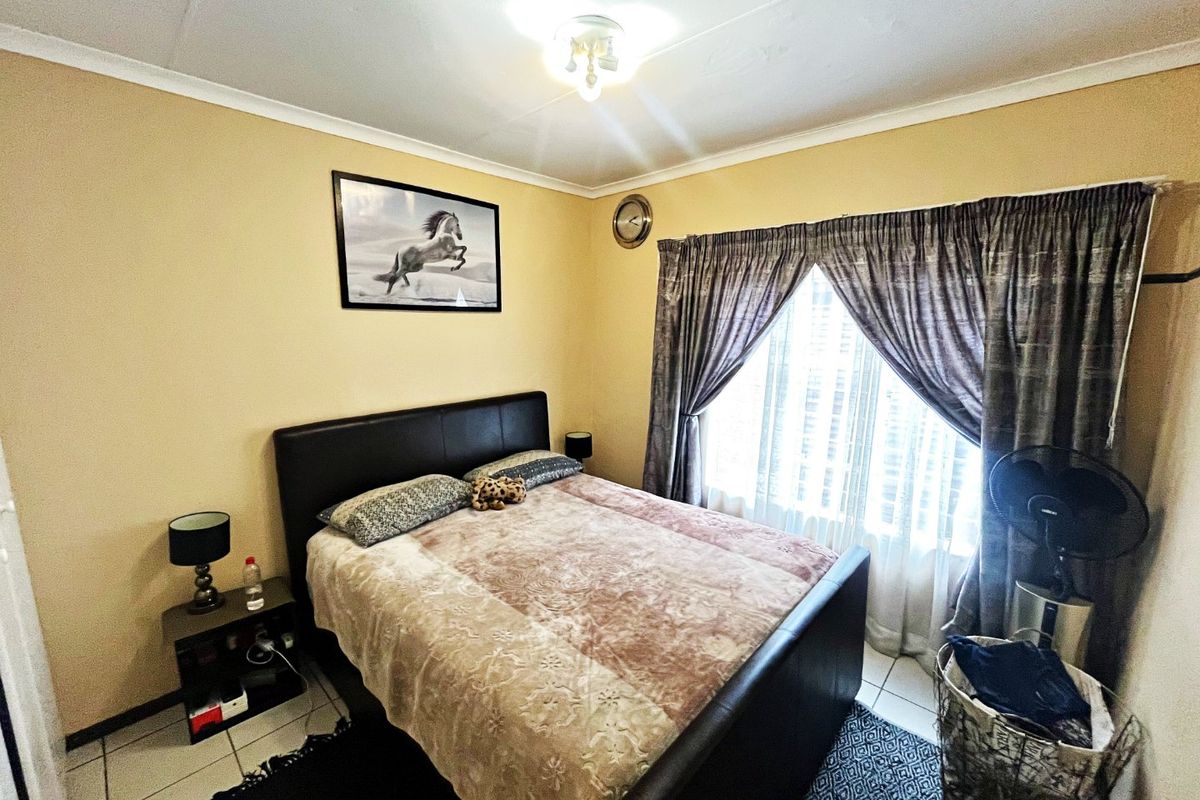 A standard bedroom featuring tiled flooring, neutral wall paint, and window treatments, offering a functional space ready for personalization.