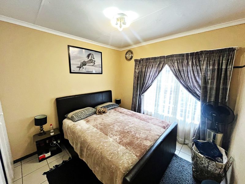 A standard bedroom featuring tiled flooring, neutral wall paint, and window treatments, offering a functional space ready for personalization.
