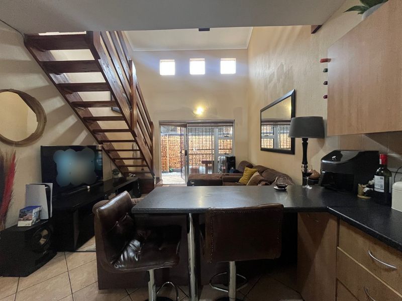 Open-plan living area featuring a wooden staircase, kitchen breakfast bar, and direct access to a rear patio through sliding glass doors.