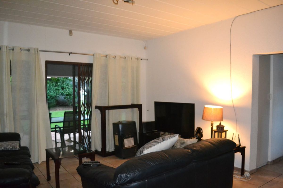 A living room featuring tiled flooring and a sliding glass door providing access to the outdoor area.