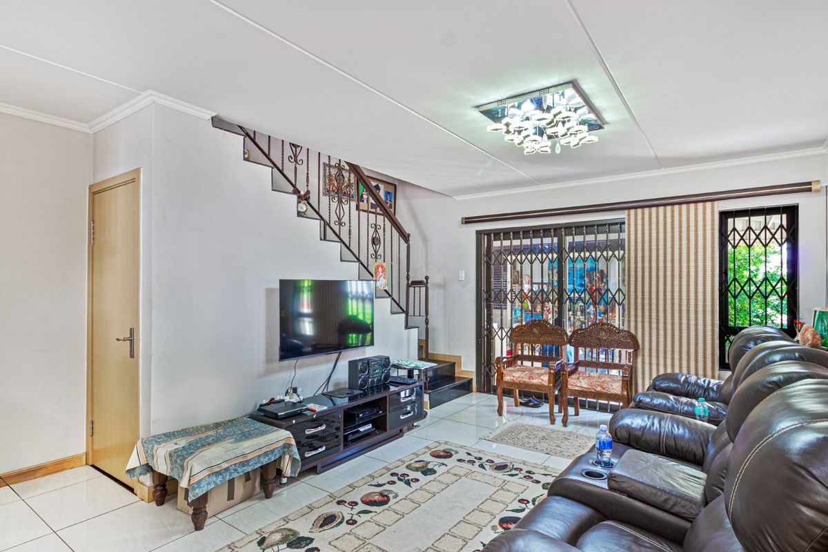 A living room featuring tiled flooring, a staircase with a wrought iron balustrade, and a sliding glass door leading to an outdoor area.