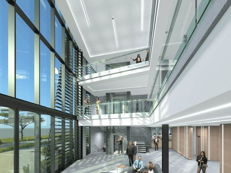 Modern multi-level commercial atrium featuring a full-height glass facade, glass balustrades, and contemporary recessed lighting in a spacious, open-plan lobby area.