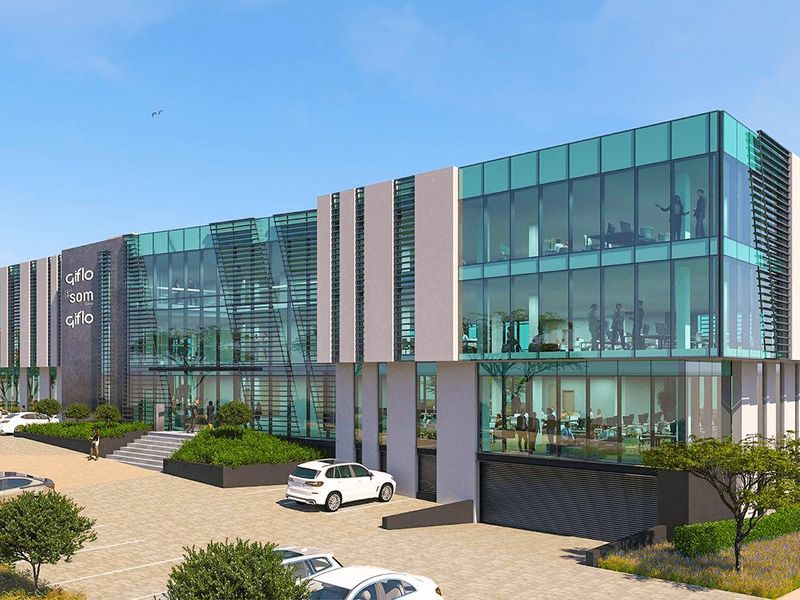 Modern commercial office building featuring a glass curtain wall facade, paved parking area, and landscaped garden beds.