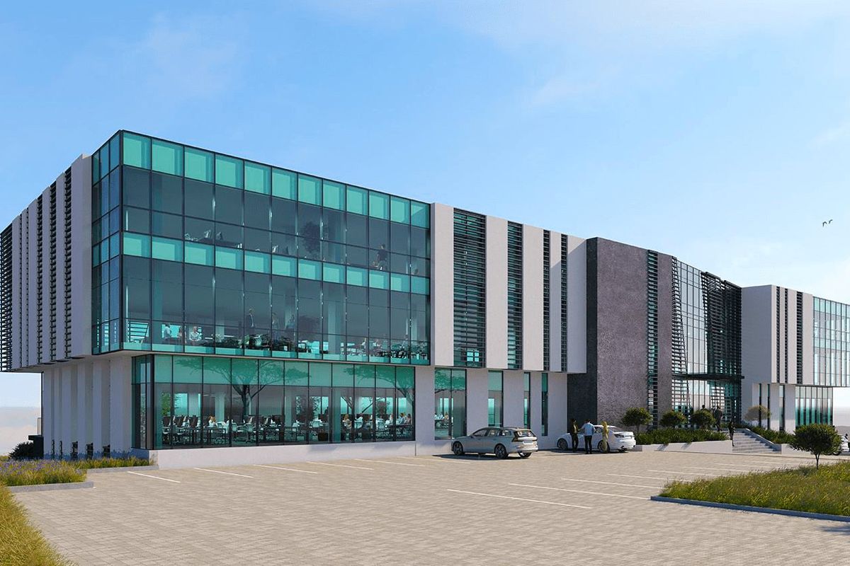 Modern multi-story commercial office building featuring extensive glass curtain walls, stone cladding, and a spacious paved parking area.