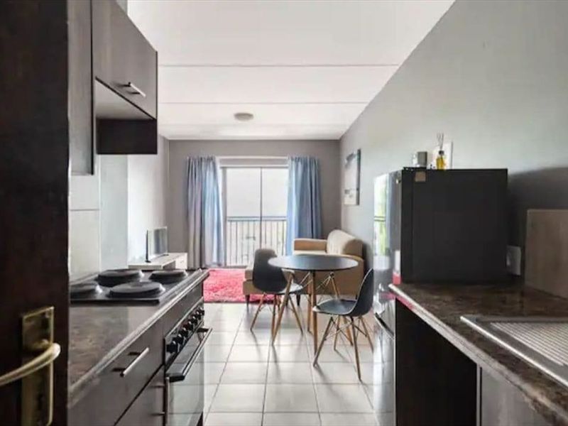 Open-plan kitchen and living area featuring tiled flooring, built-in cabinetry, and a sliding door leading to a balcony.