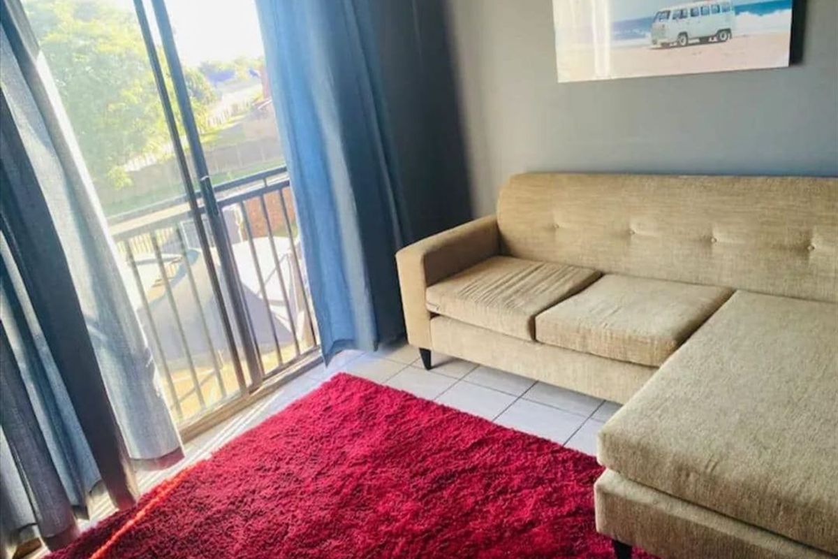 A living room area featuring tiled flooring and a sliding glass door providing access to an attached balcony.