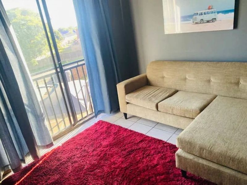 A living room area featuring tiled flooring and a sliding glass door providing access to an attached balcony.