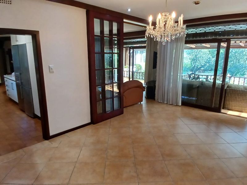 Spacious living area featuring tiled flooring, elegant chandelier lighting, and large sliding glass doors providing access to the outdoor patio area.