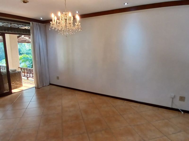 Spacious living area featuring ceramic tile flooring, crown molding, and large sliding glass doors providing access to an outdoor patio.