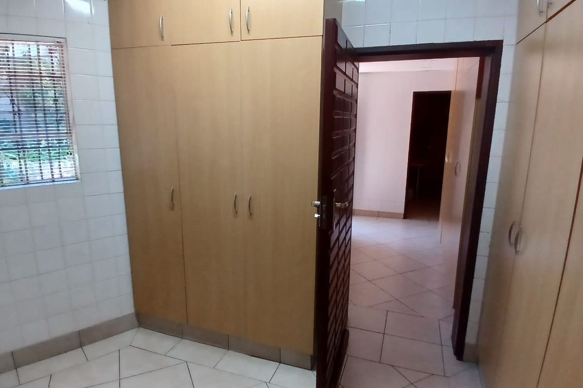 A functional bedroom space featuring extensive built-in cabinetry, tiled walls, and neutral floor tiles, offering a clean and practical layout.