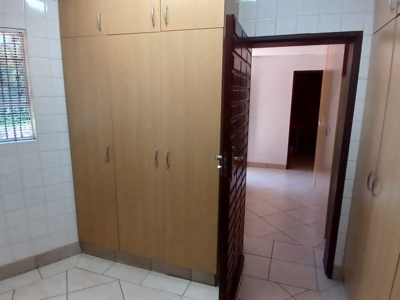 A functional bedroom space featuring extensive built-in cabinetry, tiled walls, and neutral floor tiles, offering a clean and practical layout.